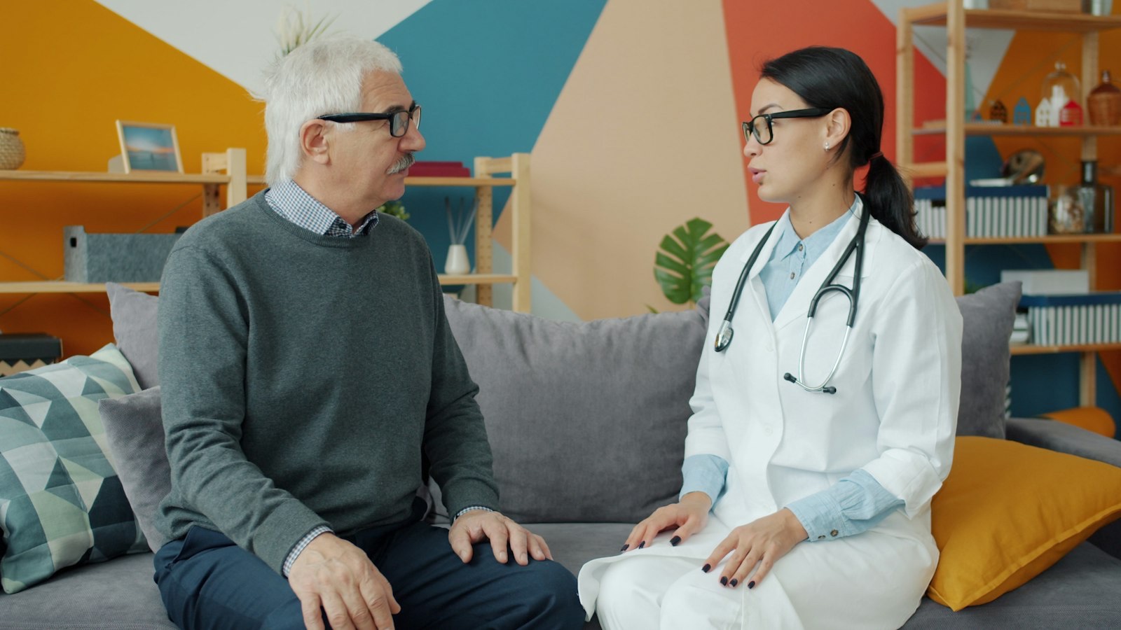 Médica conversando com paciente idoso em ambiente domiciliar
